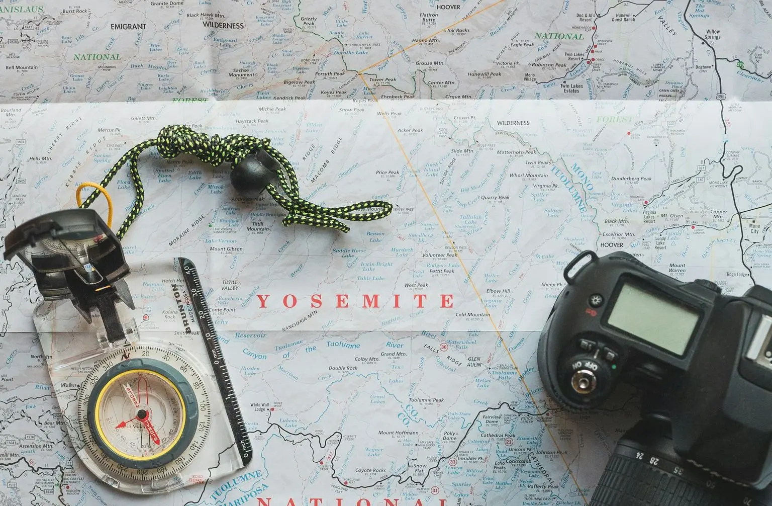 black Nikon DSLR camera beside of map compass